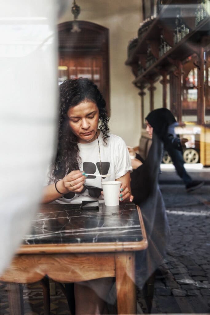 Person sitting alone at a café table reflecting on repeated relationship patterns