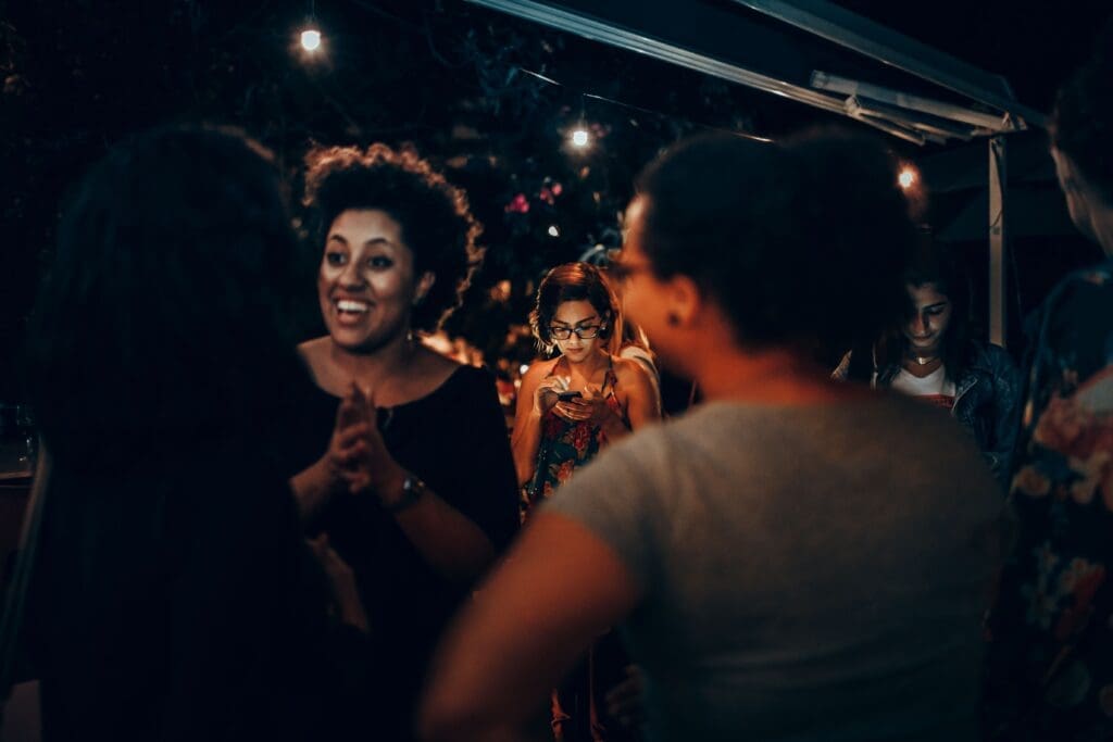 Person standing slightly apart at a social gathering, illustrating social anxiety